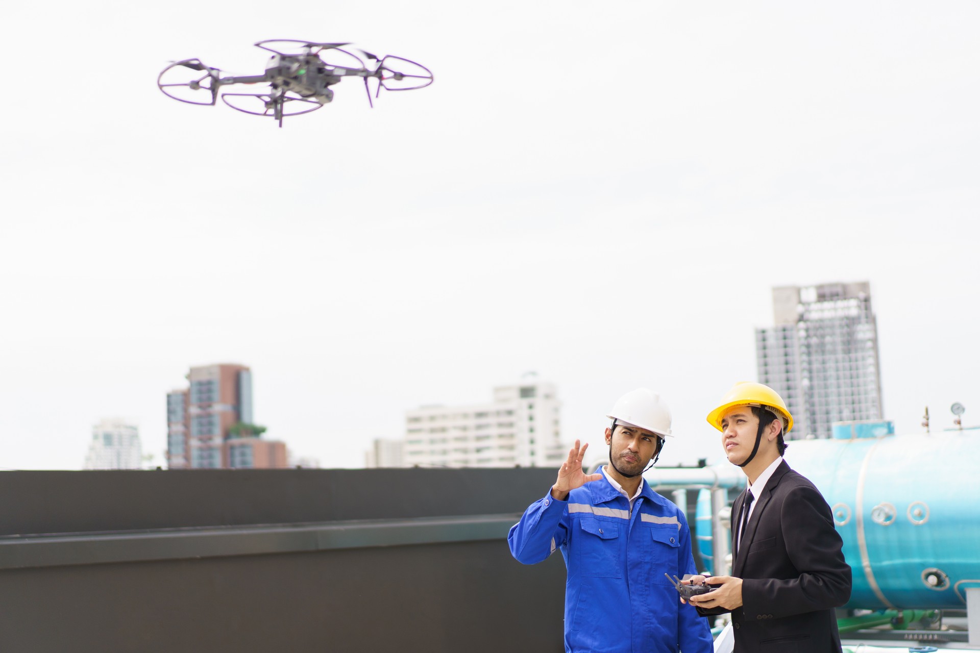 Engineer - contractor flying a UAV or drone over the building.